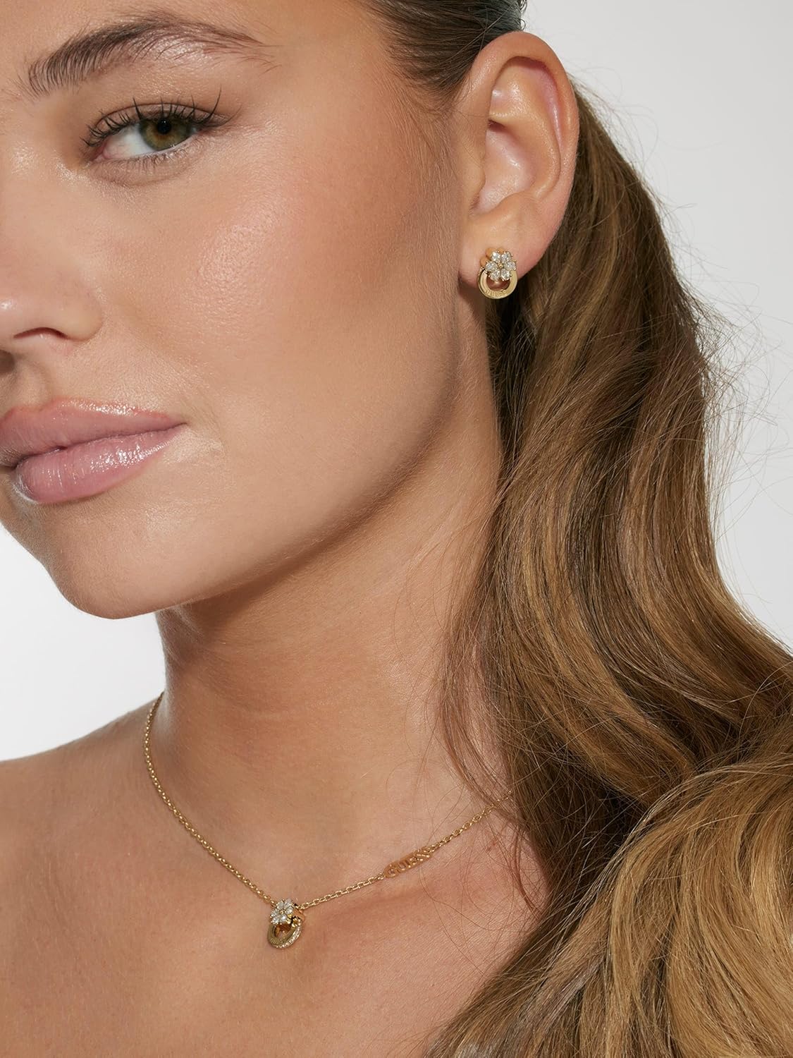 Guess Pendientes Lily Dorados – Argollas de Acero con Flor de Lirio en Cristales Blancos